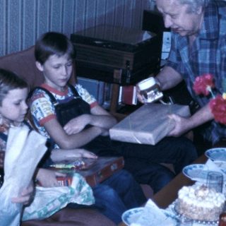Family gathering with cake and reading materials.