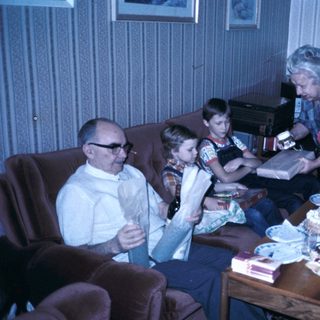 Family gathering with cake and reading materials.