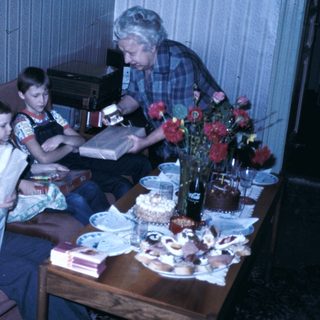 Family gathering with cake and reading materials.