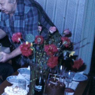 Family gathering with cake and reading materials.
