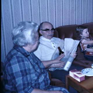 Family celebrating a birthday indoors with cake and gifts.