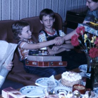 Family celebrating a birthday indoors with cake and gifts.