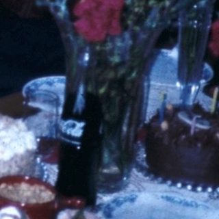 Family celebrating a birthday indoors with cake and gifts.