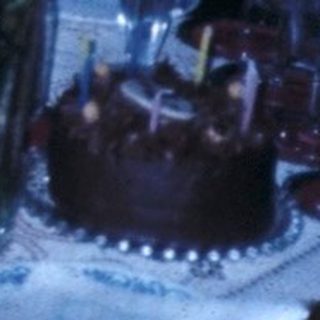 Family celebrating a birthday indoors with cake and gifts.