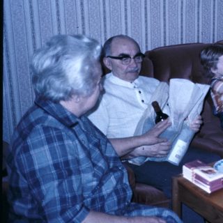 Family celebrating a birthday indoors with cake and gifts.