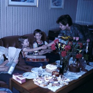 Family celebrating a birthday indoors with cake and gifts.