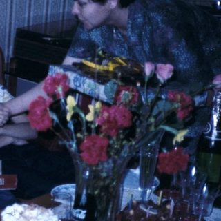 Family celebrating a birthday indoors with cake and gifts.
