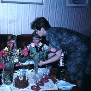 Family gathering celebrating with cake and flowers.