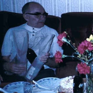 Family gathering celebrating with cake and flowers.