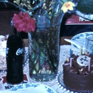 Family gathering celebrating with cake and flowers.