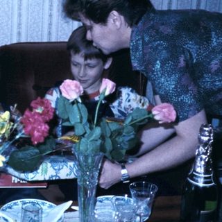 Family gathering celebrating with cake and flowers.