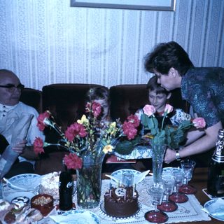 Family gathering celebrating with cake and flowers.