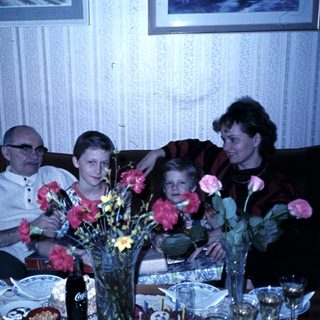 Family gathering with flowers on dining table.