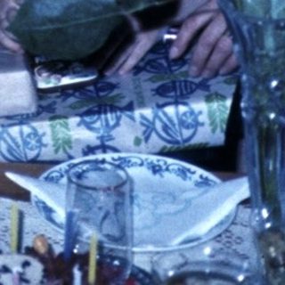Family gathering with flowers on dining table.