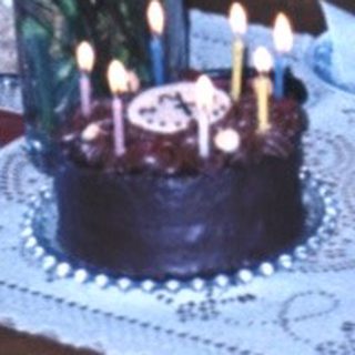 Family celebrating birthday with candles and flowers.