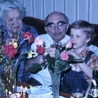 Family celebrating birthday with candles and flowers.