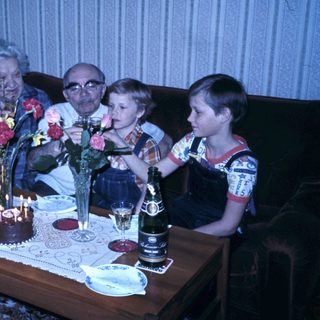 Family celebrating birthday with candles and flowers.