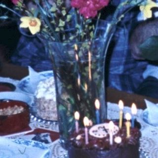 Family celebrating birthday with candles and flowers.