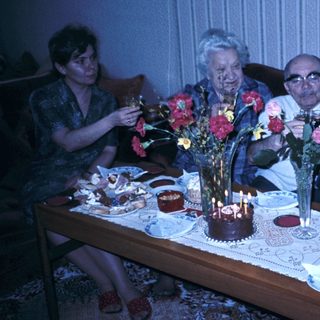 Family celebrating birthday with candles and flowers.