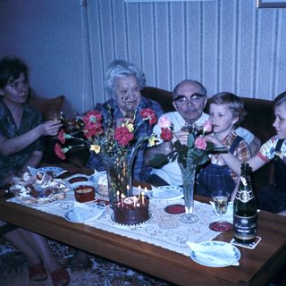 Family celebrating birthday with candles and flowers.