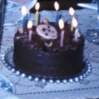 Family celebrating birthday with cake and drinks.