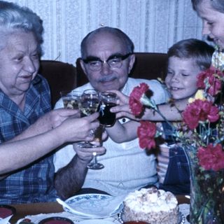 Family celebrating birthday with cake and drinks.