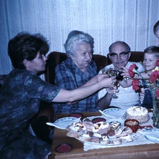 Family celebrating birthday with cake and drinks.