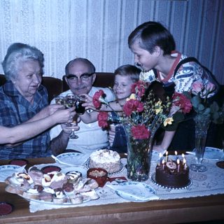 Family celebrating birthday with cake and drinks.