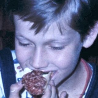 Two boys eating cake with flowers on table.