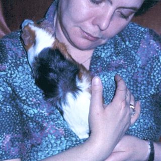 Woman cradling sleeping kitten indoors.