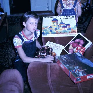Two children holding travel brochures and books indoors.