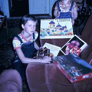 Two children holding travel brochures and books indoors.
