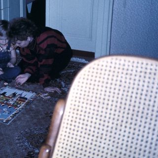 Three people assembling a puzzle on the floor.