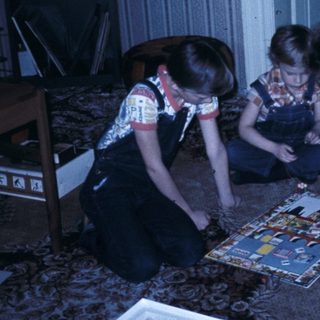 Three people assembling a puzzle on the floor.