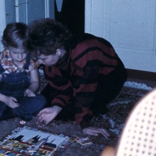 Three people assembling a puzzle on the floor.