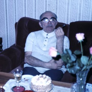 Elderly couple celebrating with cake and flowers.