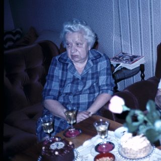 Two elderly people celebrating with cakes indoors.