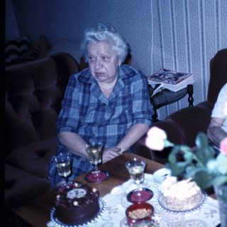 Two elderly people celebrating with cakes indoors.