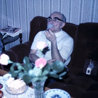 Two elderly people celebrating with cakes indoors.