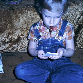 Young child playing handheld game on floor.