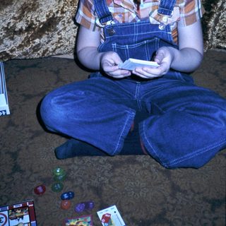 Young child playing handheld game on floor.
