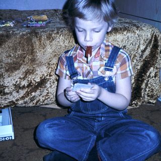 Boy playing with small handheld device.