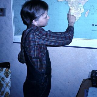 Boy pointing at world map.