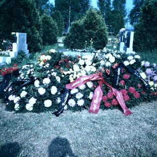 Memorial wreaths and flowers on gravesite.
