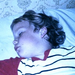 Child peacefully sleeping in striped pajamas.