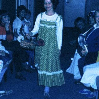 Group celebration with woman in traditional dress distributing treats.