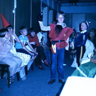 Children dressed in costumes performing on stage.