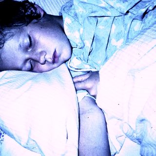 A child peacefully sleeping under a blanket.