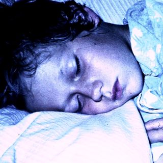 A child peacefully sleeping under a blanket.