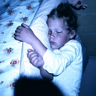 Child peacefully sleeping in bed at night.
